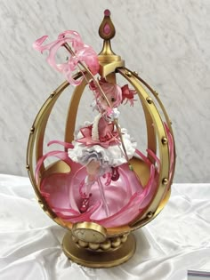 a pink and gold figurine sitting on top of a white cloth covered table