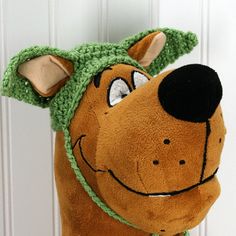 a stuffed dog with a green hat on it's head hanging from a door handle