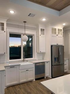 a kitchen with white cabinets and stainless steel appliances in the middle of an open floor plan