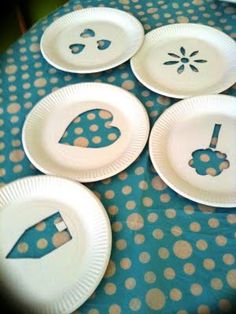 paper plates with cut out designs on them sitting on a blue tablecloth covered table