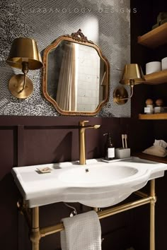 a white sink sitting under a mirror next to a gold faucet in a bathroom