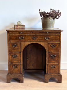 an old wooden desk with drawers and a potted plant sitting on top of it