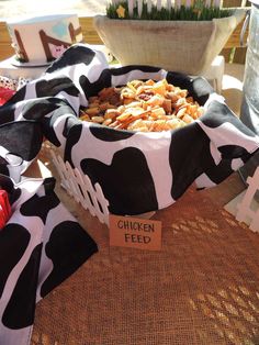 a bowl filled with chicken feed sitting on top of a table covered in cow print