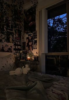 an unmade bed with pictures on the wall and candles lit in front of it