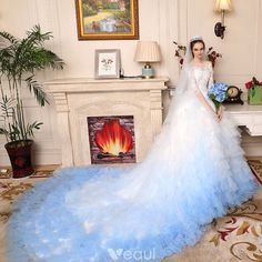 a woman in a blue wedding dress standing next to a fireplace with flowers on it