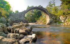 a stone bridge over a river surrounded by rocks