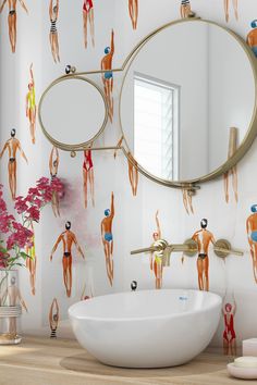 a bathroom sink sitting under a mirror next to a wall paper with people on it