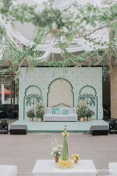 an outdoor stage set up for a wedding with flowers and greenery on the side