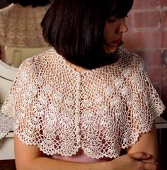 a woman standing in front of a mirror wearing a white crochet top with short sleeves