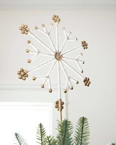 a christmas ornament hanging from the ceiling with pine cones and bells on it