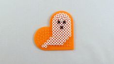 an orange brooch with a white dog on it's face and the word love spelled in small circles