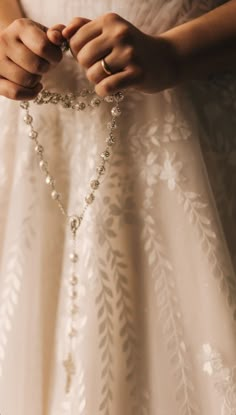 a close up of a person wearing a dress and holding a rosary in their hands