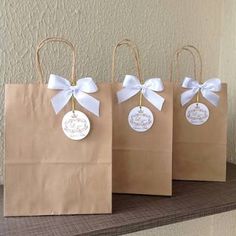 three brown paper bags with white bows and tags on them, sitting on a shelf