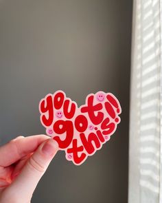 someone holding up a sticker with the words you got this written on it in red