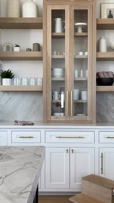 a kitchen with marble counter tops and wooden cabinets in the center, along with white cupboards