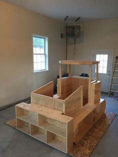 an unfinished wooden structure is being built in a room with two windows and ladders