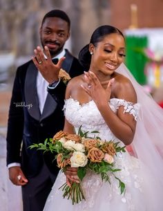 a bride and groom standing together in front of a building with their hands up to the camera