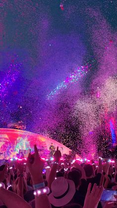 the crowd is watching fireworks and confetti being thrown into the air at an outdoor concert