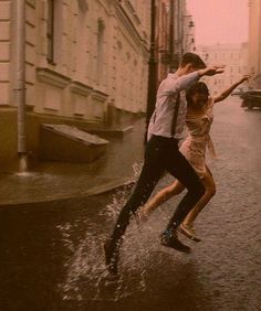 two people jumping in the air on a city street