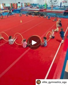 some kids are doing tricks on rings in an indoor gymnastics gym while others watch from the sidelines