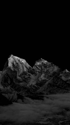 black and white photograph of snow covered mountains at night with dark sky in the background