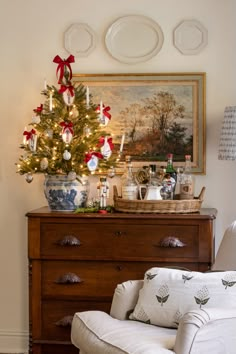 a living room with a christmas tree on top of a dresser next to a couch