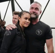 a man and woman standing next to each other with their arms around each other in front of them