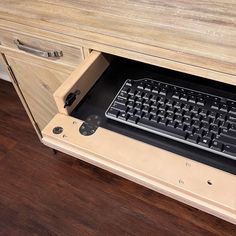 a computer desk with a keyboard and mouse on it's side drawer in front of a wooden cabinet