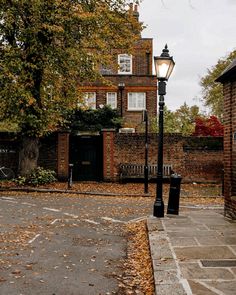 a street light sitting on the side of a road next to a tree and brick building