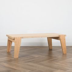 a wooden bench sitting on top of a hard wood floor next to a white wall