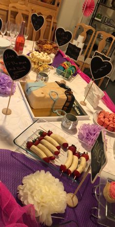 a table topped with cakes and desserts on top of a purple cloth covered table