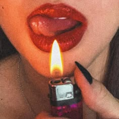 a woman holding a lighter in her mouth with the light on it's side