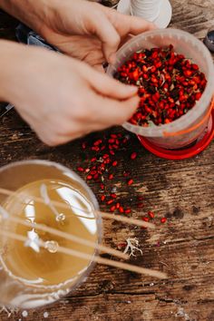 two hands picking seeds out of a container with chopsticks next to it on a wooden table