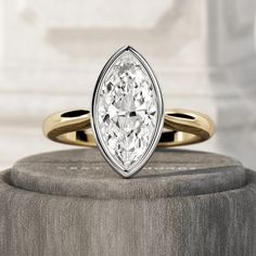 a pear shaped diamond ring sitting on top of a stone