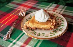 a piece of pie with whipped cream on top sits on a plate next to a fork