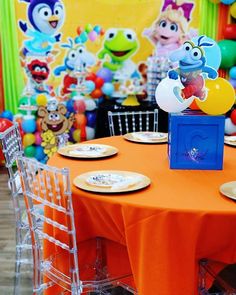 an orange table topped with plates covered in cartoon character paper cutouts and plastic chairs