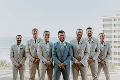 a group of men standing next to each other in front of a building near the ocean