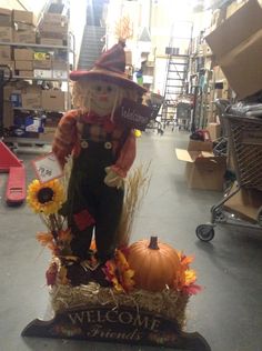 a scarecrow statue sitting on top of a pumpkin