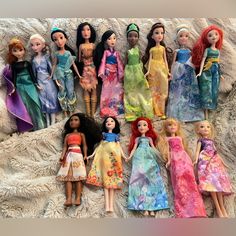 there are many dolls lined up together on the bed sheet in this photo, all wearing different dresses