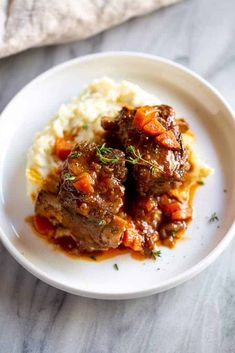 a white plate topped with meat and mashed potatoes