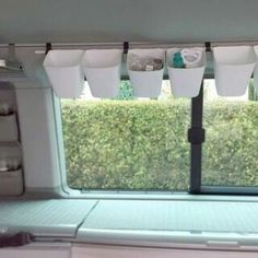 the inside of a camper with several cups hanging from it's window sill