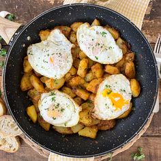 fried eggs and potatoes in a skillet on a wooden table