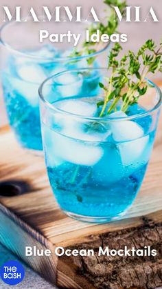 two glasses filled with blue ocean cocktails on top of a cutting board