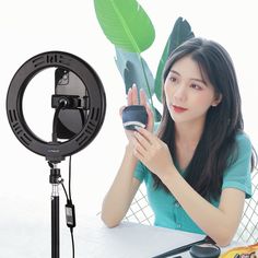 a woman sitting at a table in front of a camera with a plant on it