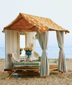 a bed sitting on top of a sandy beach next to the ocean in front of a tent