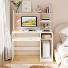 a white desk with a computer on top of it next to a bed and window