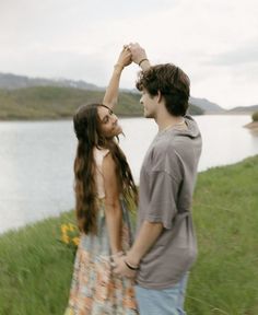 a man and woman standing next to each other in front of a body of water