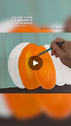 someone is painting an orange pumpkin with white paint