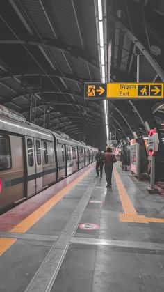 two people are walking towards a train at the station