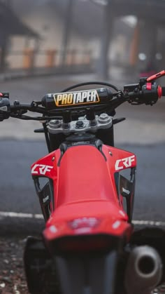 a red dirt bike parked next to a street